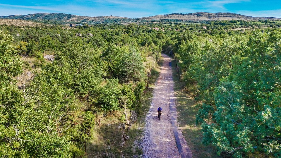 Cycliste gravel sur route rustique du Larzac