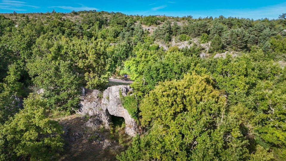 Cycliste gravel sur piste à coté de la pierre trouée du Cros